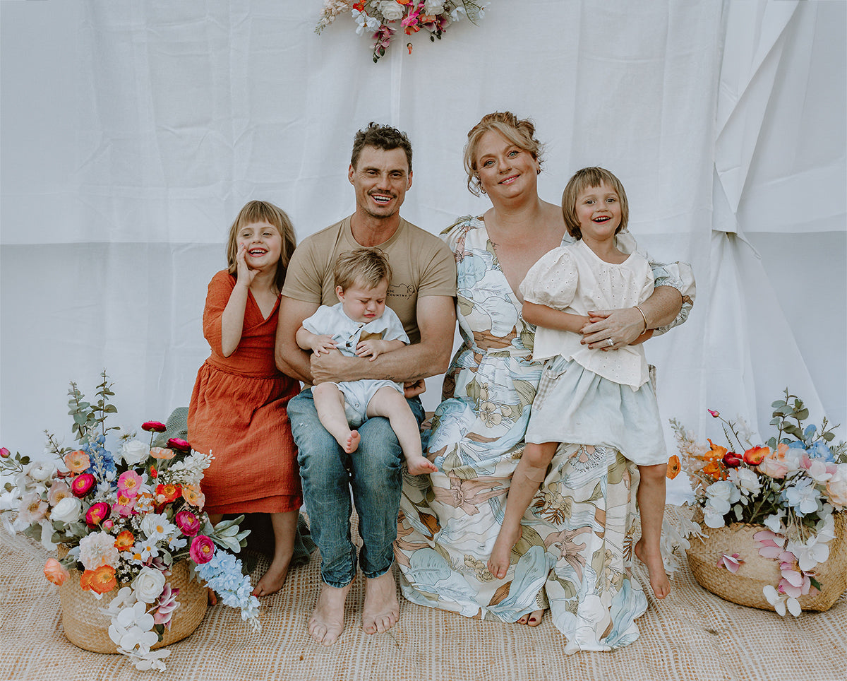 Cozie Dozie Co. founder Emma James-Skey with her husband and children surrounded by native floral arrangements in Central Queensland.