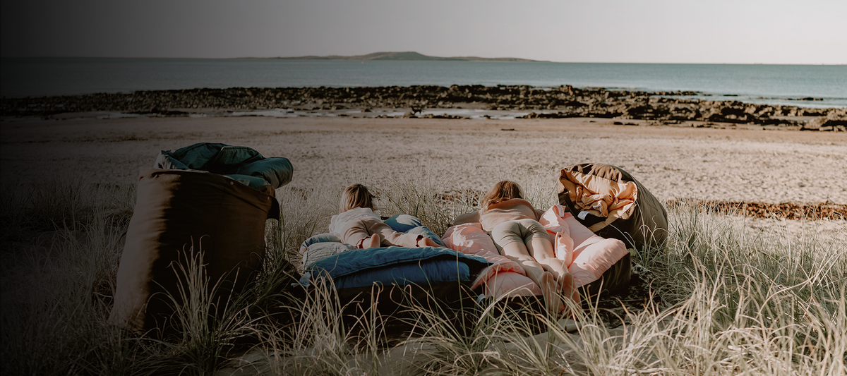 Children relaxing on Cozie Dozie Co. Joey adventure loungers in BowerBird Blue and Quartz among the sand dunes along the Central Queensland coastline.