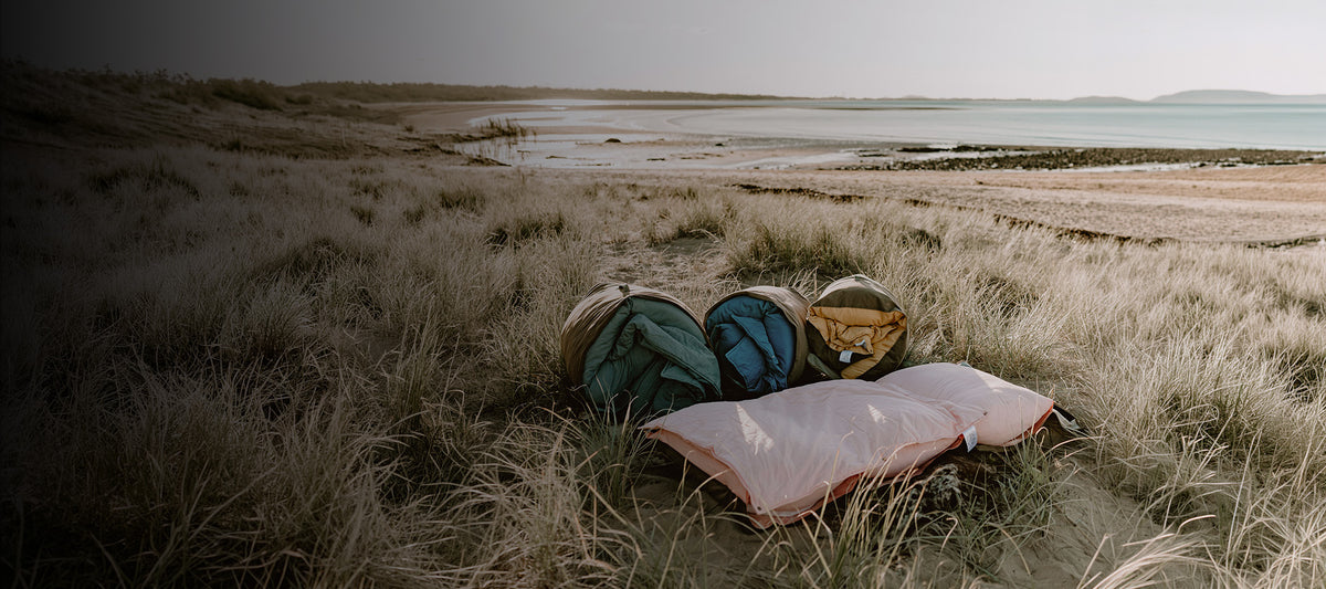 Rolled Cozie Dozie Co. adventure lounger cover packed in canvas straps resting in field grass for the shipping information page.