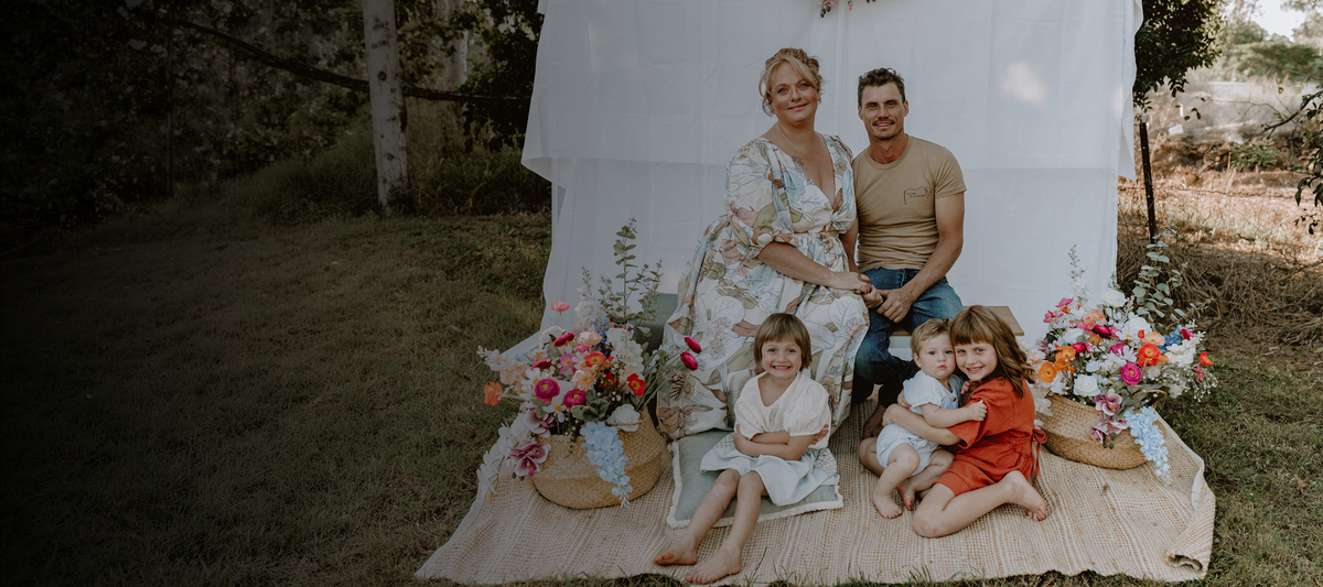 Cozie Dozie Co. founder Emma James-Skey and her family sitting together outdoors in Mount Larcom, Central Queensland, representing the brand's origin story.