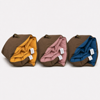 Three rolled Cozie Dozie Co. Colour of Country Joey adventure loungers lined up in Ochre, Quartz, and BowerBird Blue with brown canvas backing.